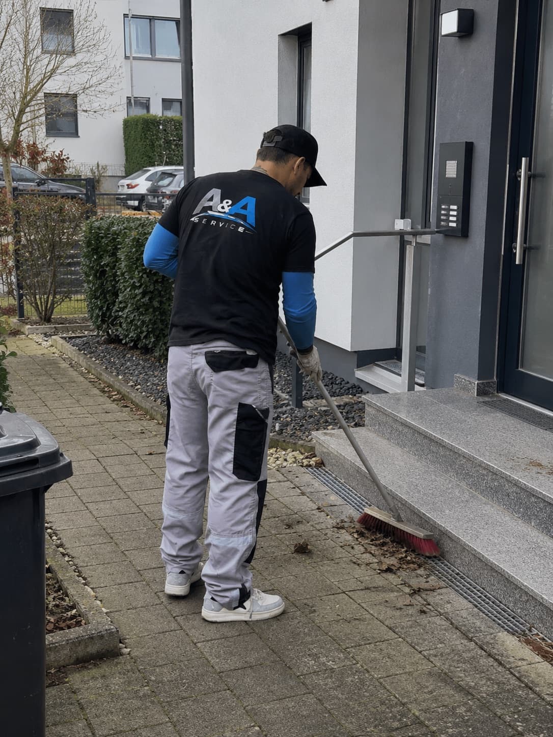 A&A Service Mitarbeiter kehrt den Eingangsbereich eines Wohnhauses